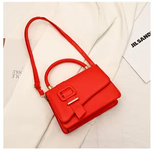 Detail van rode crossbodytas met vierkante gesp en goudkleurige metalen afwerkingen