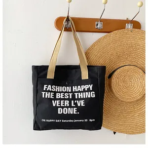 Detail of black canvas tote bag with beige woven handles and white artistic print