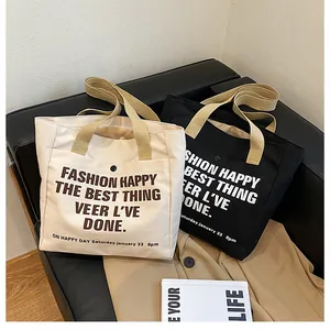 Detail of canvas tote bags in cream and black with thick handles and front pocket