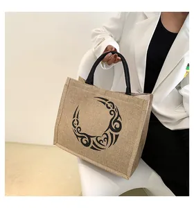 Detalle del bolso tote de yute con motivo de tótem negro y asas circulares de mujer