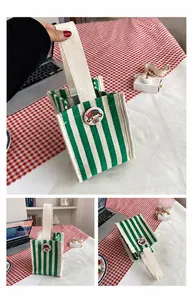 Detailed views of the green striped canvas handbag with a round cartoon badge decoration