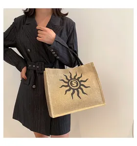 Detalle de un bolso tote de yute grande con estampado de sol negro y asas de tela