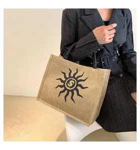 Bolso tote grande de yute trenzado con logo de sol negro y asas negras en detalle real