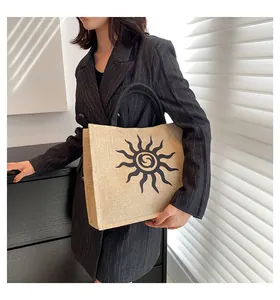 Detalle del bolso tote de lona con patrón de sol negro y asas trenzadas