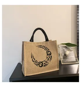 Detalle del bolso tote de yute con tótem de luna negra y asas redondas tejidas