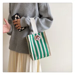 Detailed view of green and white striped canvas tote with cute cartoon badge detail
