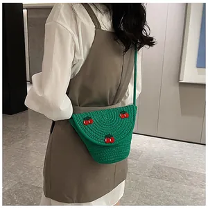Détail d'un sac bandoulière tissé vert avec broderie de cerises 3D et texture fine