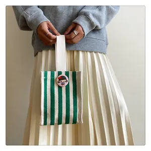 Detail of mini striped canvas bag with cute cartoon badge held by a model