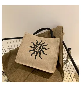 Detalle de bolso tote de yute con diseño de sol en un carrito de compras metálico