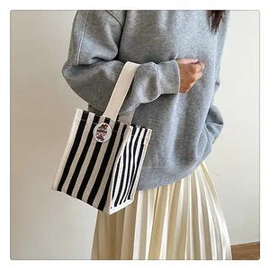 Detail shot of black and white striped canvas handbag with cute character brooch