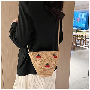 Détail du sac à bandoulière en paille fait main avec broderie de cerises rouges et texture