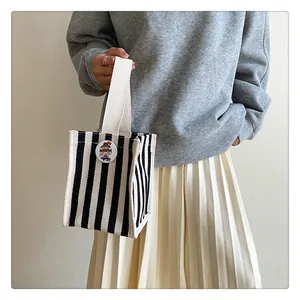 Detail of a mini striped canvas tote bag featuring a cartoon badge and woven handles