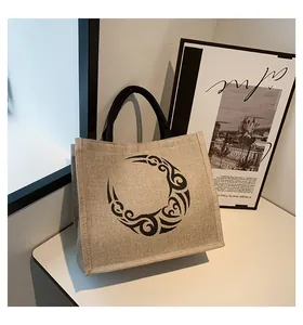 Detalle del bolso tote de yute con tótem tribal negro y asas circulares en estudio