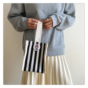 Detail of canvas bag with black and white vertical stripes and round cartoon brooch