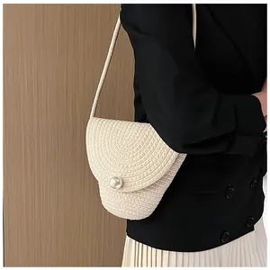 Détail d'un sac en paille tissée beige avec bouton perle fantaisie et rabat élégant
