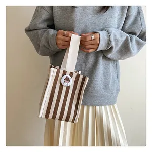 Mini striped canvas tote bag detail with circular cartoon badge and webbing handle