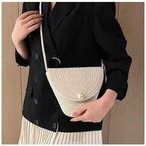 Détail du sac bandoulière en paille tressée avec boucle en perle et texture crème élégante
