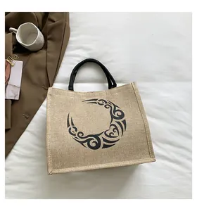 Primer plano de bolso tote de lino con motivo de luna creciente y asas redondas negras