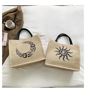 Detalle de dos bolsos de lona con estampados de sol y luna sobre sábanas blancas