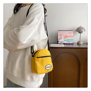 Primer plano del bolso bandolera de lona amarilla con logotipo Fashion y correa negra ajustable