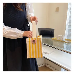 Detail of yellow striped canvas mini tote bag with a cute cartoon badge and carry handle
