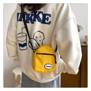Detalle de un mini bolso bandolera amarillo brillante con cremallera negra y etiqueta