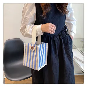 Detail view of a blue striped canvas tote bag with a cute round badge in a lifestyle setting