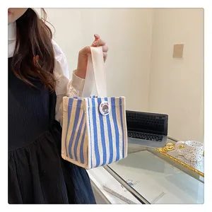 Close-up of a blue and beige striped canvas handbag with a cartoon badge in a cozy office setting