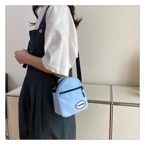 Detalle del mini bolso bandolera de nylon azul claro con parche de moda y correa negra