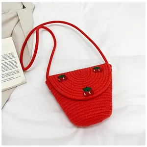 Détail du sac en paille tissée rouge avec broderie cerise et bandoulière