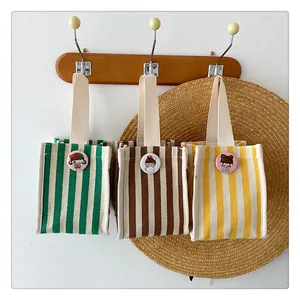 Detailed shot of striped canvas mini handbags with cute cartoon badges on a wall hook