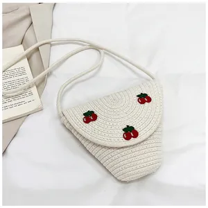 Gros plan sur un sac bandoulière blanc tissé avec détails de broderie cerise rouge