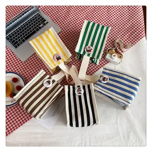 Flat lay of colorful striped canvas mini bags with cute cartoon badges on a table
