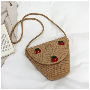Détail d'un sac bandoulière en paille avec cerises brodées et bandoulière assortie