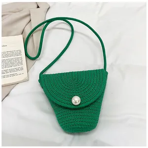 Détail du mini sac bandoulière en paille tressée verte avec une grande perle décorative