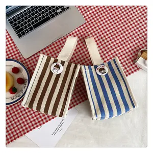 Detail of canvas pouches with cartoon badges on red checkered and white table