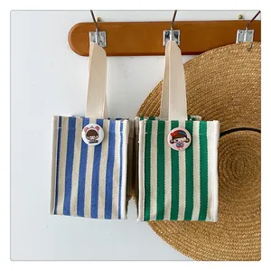 Close-up of small striped canvas storage bags with cute cartoon badges on wooden hooks