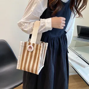 Striped canvas mini handbag for women with cartoon pin and wide cream handles