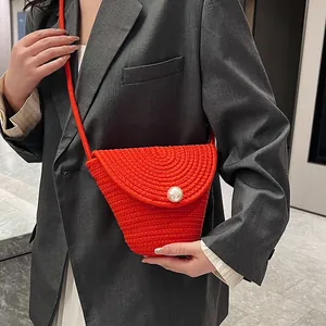 Sac à bandoulière en paille orange tissé main avec boucle perle sur veste grise