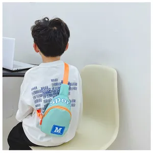 Rückansicht eines Jungen mit einer minzgrünen Crossbody-Tasche auf einem weißen Stuhl