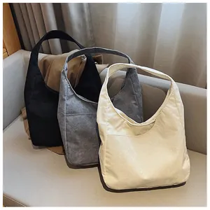 Drei Cord-Einkaufstaschen in Schwarz, Grau und Beige auf einem modernen Sofa