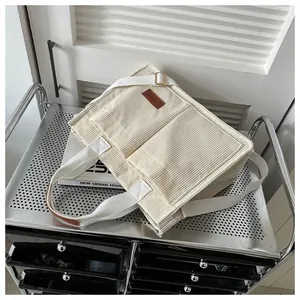 Detail of off-white corduroy tote bag texture with front pockets and fashion leather label