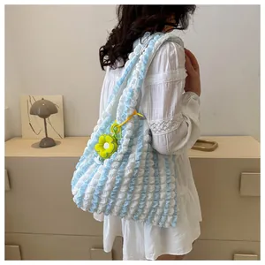 Detail of blue and white pleated tote bag with a yellow sunflower charm on shoulder