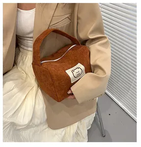 Dettaglio della borsa cosmetica in velluto a coste marrone con patch a forma di orso