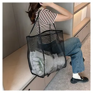 Détail du grand sac de plage en maille noire montrant sa capacité et sa texture transparente