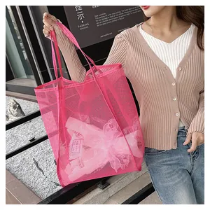 Gros plan d'un sac cabas en maille rose rouge montrant le matériau en nylon et sa grande taille