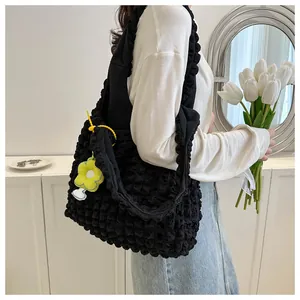 Model wearing black popcorn fabric shoulder bag with yellow flower charm detail