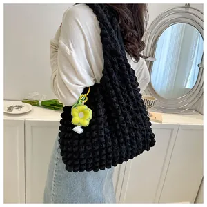 Detail of black pleated bubble shoulder bag with a yellow flower charm accessory
