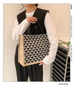 Detail of linen tote bag featuring black geometric triangles and round handles for commute