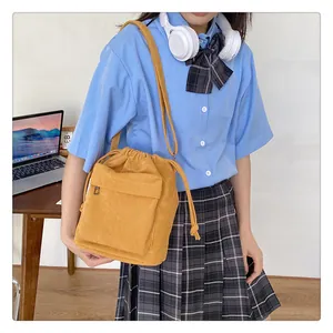 Détail d'un sac seau en velours côtelé jaune dans un décor de vie étudiante